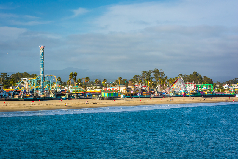 Amusement park rides line a sandy beach along the ocean